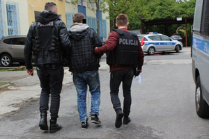 Policjanci prowadzą zatrzymanego mężczyznę