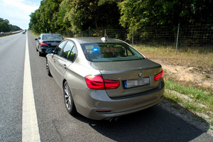 przy drodze stoi kontrolowany pojazd, a za nim policyjne bmw