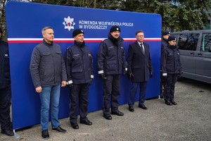 Policjanci stojący na tle baneru.