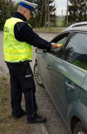 Policjant Wydziału Ruchu Drogowego Komendy Miejskiej Policji w 
Toruniu, przy użyciu urządzenia alkoblow kontroluje stan trzeźwości kierowcy.