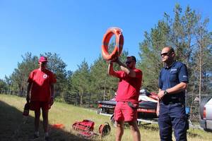 Policjant i ratownicy wodni pokazują dzieciom koło ratunkowe