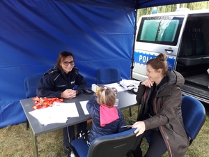 Policjantka rozmawia z dziewczynką w stoisku profilaktycznym