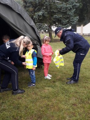 policjanci wręczają kamizelki odblaskowe