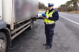 kontrola drogowa pojazdu dostawczego z użyciem analiztora spalin. Na zdjęciu umundurowany funkcjonariusz i samochód