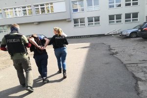 Policjantka i policjant prowadzą zatrzymanego 21 latka.