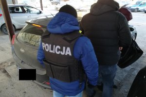 Policjanci prowadzą podejrzewanego o dokonanie zabójstwa.