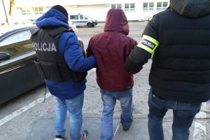 Policjanci prowadzą podejrzewanego o dokonanie zabójstwa.