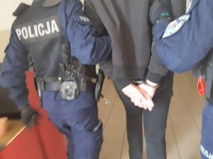 policjanci prowadza zatrzymanego wandala do zniszczenia pomnika Jana Pawła II