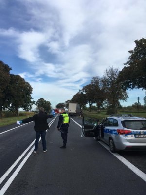 Zdjęcia ze śmiertelnego  wypadku w Ostaszewie pod Toruniem. NA zdjęciach pojazdy i funkcjonariusze  służby takich  jak policja straż pożarna, inspekcja transportu drogowego, holownik. Na pierwszym planie policjant rozmawiający ze świadkiem. W oddali miejsce zdarzenia.