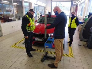 Policjanci podczas kontroli świateł w pojazdach  na polnej drodze, na trasie oraz w salonie biorącym udział w akcji Skoda w Lubiczu podczas ustawiania świateł przez diagnostę.