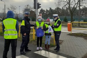 policjanci na przejściu dla pieszych wręczają torby dwójce dzieci