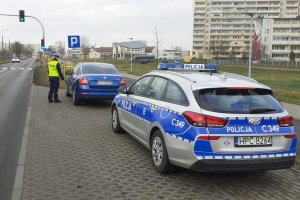 kontrola policyjna samochodu, pobocze drogi - zatoczka, przy kontrolowanym samochodzie stoi policjantka