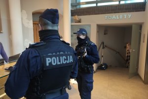 hotelowe lobby, policjant i policjantka stoją przy recepcji