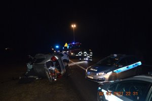 Zdjęcia z miejsca wypadku w Brzozi. Widoczne mocno uszkodzone  pojazdy zwłaszcza z przodu podczas czołowego zderzenia. Widoczne obok lub w oddali pojazdy policji i straży pożarnej.