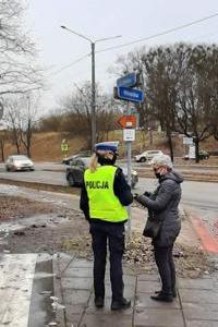 Policjantka  podczas akcji Niechroniony Uczestnik Ruchu Drogowego wręcza pieszej  opaskę odblaskową.