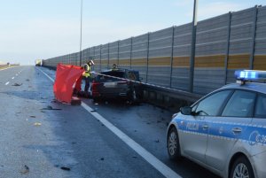 Zdjęcie z miejsca wypadku na autostradzie A1. Na zdjęciu widoczne zniszczone uderzeniem auto i pracujący na miejscu policjanci, którzy zabezpieczają ślady.