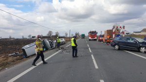 Zdjęcia z wypadku na DK 91 w Ostaszewie. Na jezdni  widoczne fragmenty pojazdu, w rowie pojazd marki mercedes koloru srebrnego. Widać również strażaków i policjantów pracujących na miejscu.