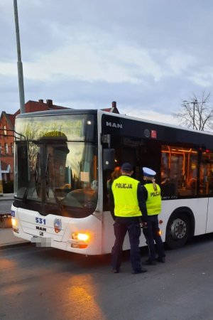 Funkcjonariusze podczas akcji związanej z bezpieczeństwem,  kontroli autobusu pod kątem przestrzegania przepisów COVID 19,