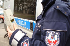 Zdjęcie poglądowe, policjant z alkomatem - miernikiem trzeźwości.