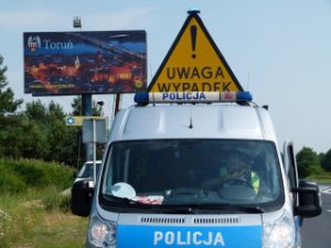 Zdjęcie  poglądowe- radiowóz policji z otwartym znakiem ostrzegawczym na dachu, &quot; UWAGA  WYPADEK&quot;.