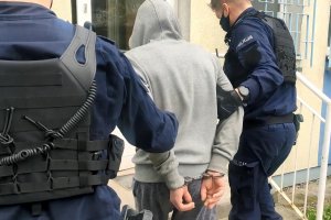 Policjanci prowadzą sprawcę kradzieży z włamaniem i wprowadzają do komisariatu.