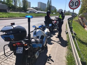 umundurowany policjant kontroluje na drodze motocyklistę