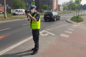 Droga, policjant  z miernikiem prędkości kontroluje pojazdy