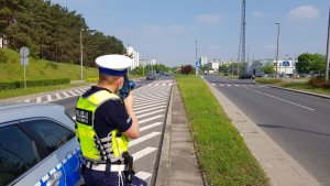 Droga, policjant  z miernikiem prędkości kontroluje pojazdy