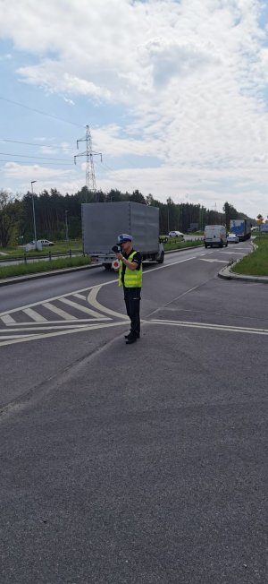 Policjant podczas akcji prędkość  z  ręcznym miernikiem prędkości. Zdjęcia pojazdów wykonane videorejestratorem   podczas przekroczenia dozwolonej prędkości.