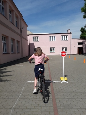 Dziewczynka na rowerze stoi przy znaku drogowym &quot;STOP&quot;