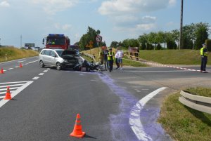 Zdjęcie z miejsca wypadku w miejscowości Wola gmina Czernikowo. Na miejscu widoczne pracujące służby ratunkowe i policja, oraz pojazdy uczestniczące w zdarzeniu czyli opel zafira i przewrócony przy nim motocykl harley davidson.