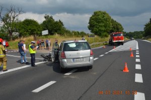 Zdjęcie z miejsca wypadku w miejscowości Wola gmina Czernikowo. Na miejscu widoczne pracujące służby ratunkowe i policja, oraz pojazdy uczestniczące w zdarzeniu czyli opel zafira i przewrócony przy nim motocykl harley davidson.