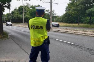 umundurowany policjant z laserowym miernikiem prędkości stoi przy drodze