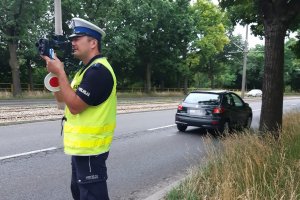 umundurowany policjant z laserowym miernikiem prędkości stoi przy drodze