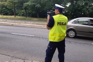umundurowany policjant z laserowym miernikiem prędkości stoi przy drodze