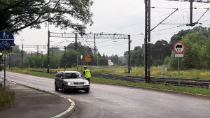 policjant przy przejeździe kolejowym kontroluje pojazdy