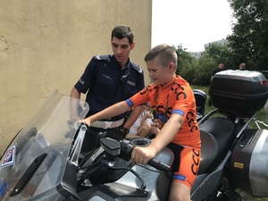 Policjant z Wydziału Ruchu Drogowego KMP w Toruniu pokazuje dziecku motocykl policyjny