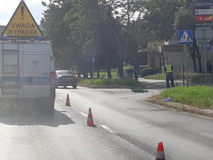 Zdjęcia z miejsca kolizji na ul. Kościuszki w Toruniu. Policjanci wykonujący czynności, radiowóz policji z napisem wypadek oraz leżąca na jezdni hulajnoga.