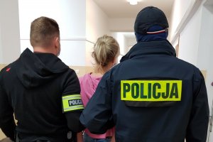 dwójka policjantów prowadzi zakutą w kajdanki kobietę