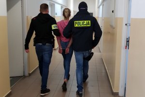 dwójka policjantów prowadzi zakutą w kajdanki kobietę