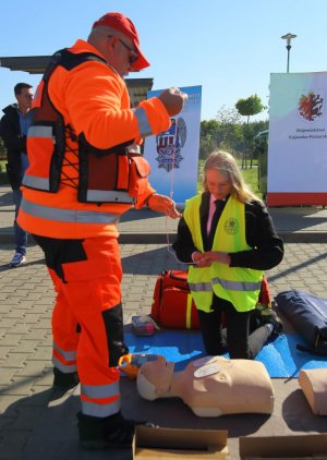 ratownik pomaga kobiecie w przeprowadzeniu pierwszej pomocy na fantomie