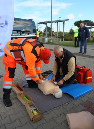 ratownik pomaga mężczyźnie przy wykonywaniu pierwszej pomocy na fantomie