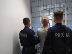 sprawca gróźb prowadzony do pomieszczenia dla osób zatrzymanych przez policjantów z Komisariatu Policji Toruń Podgórz