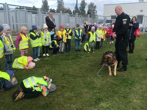 Dzieci oglądają jak policjant prowadzi pokaz tresury policyjnego psa służbowego.