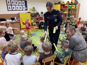 Policjantka rozdaje dzieciom elementy odblaskowe.