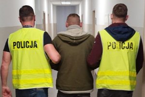 policjanci w kamizelkach odblaskowych prowadzą podejrzanego