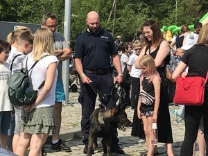 Policjant z psem policyjnym opowiada uczestnikom festynu o pracy z psem policyjnym