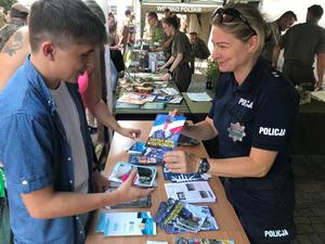 Policjantka wręcza mężczyźnie ulotkę informacyjną dotyczącą służby w policji