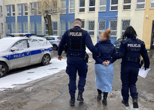 dwóch policjantów prowadzi zatrzymaną