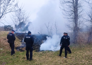 policjanci gaszą pożar łąki